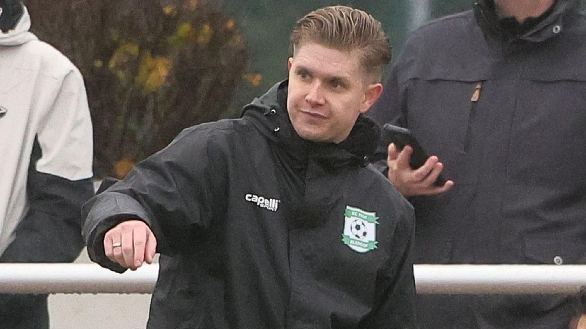 Das Foto zeigt den Elsdorfer Trainer, der warnend den Arm ausstreckt.