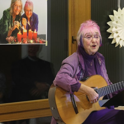 Monika Kampmann sitz mit ihrer Gitarre vor einem Notenständer und singt.
