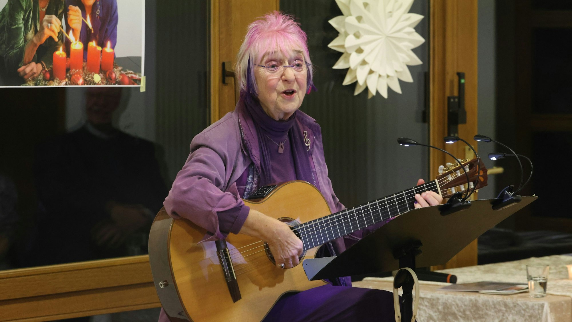 Monika Kampmann sitz mit ihrer Gitarre vor einem Notenständer und singt.
