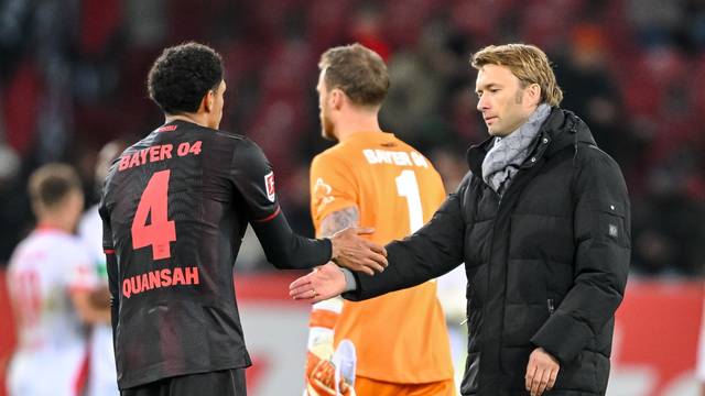 Jarell Quansah (l, Bayer Leverkusen), Torwart Mark Flekken (Bayer Leverkusen) und Geschäftsführer Sport Simon Rolfes (Bayer Leverkusen) klatschen sich nach dem 0:2 in Augsburg enttäuscht ab.