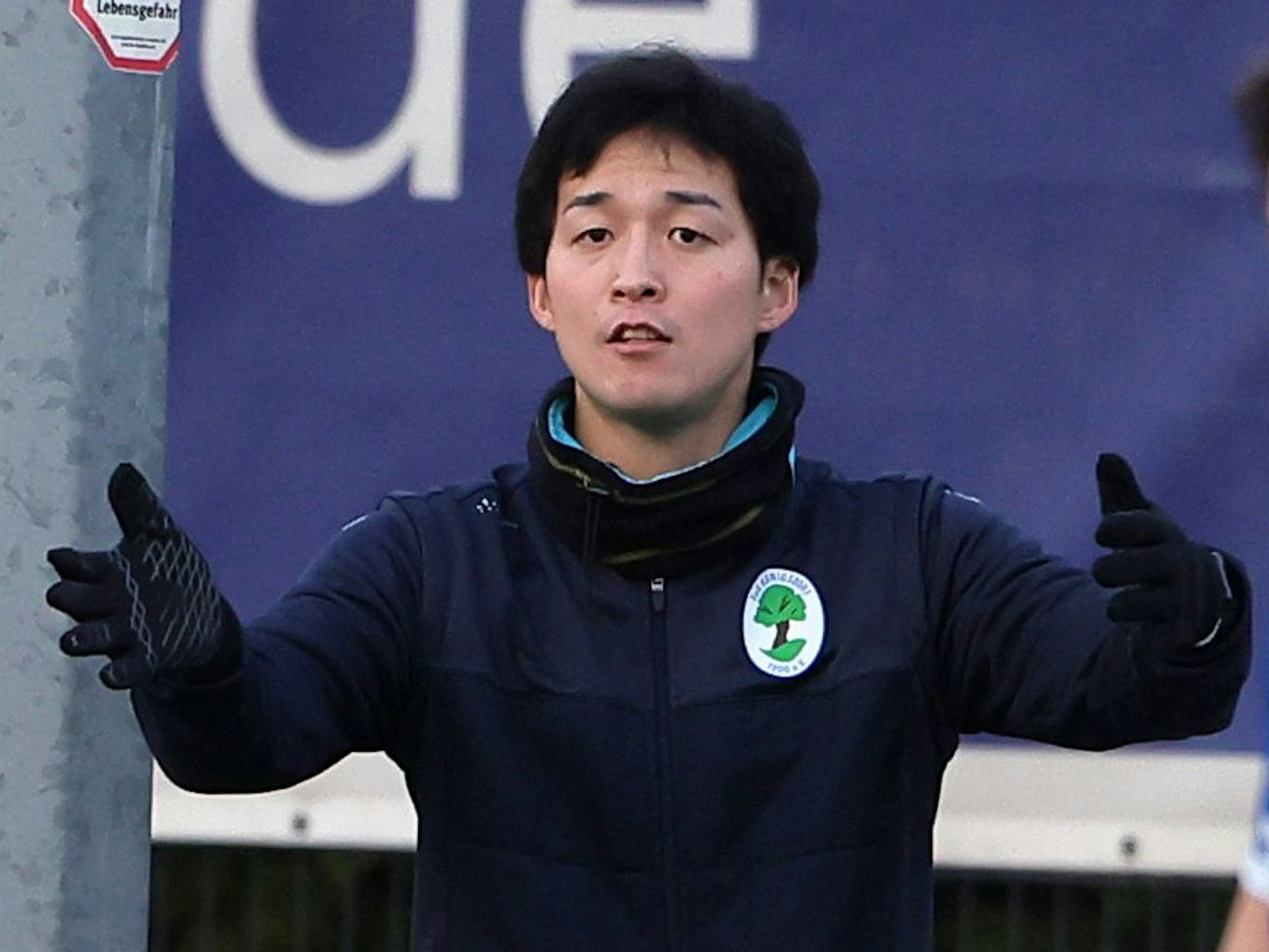 Das Foto zeigt einen Trainer, der mit seinen Armen gestikuliert.