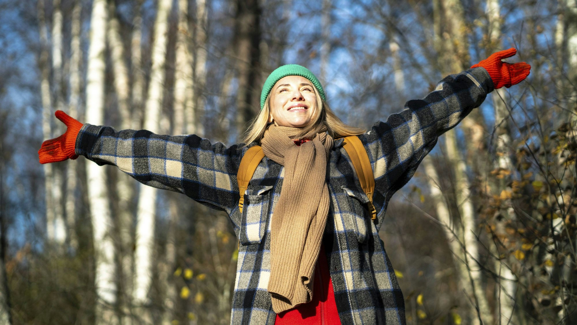 Eine Frau hebt die Arme und lächelt. (Symbolbild)