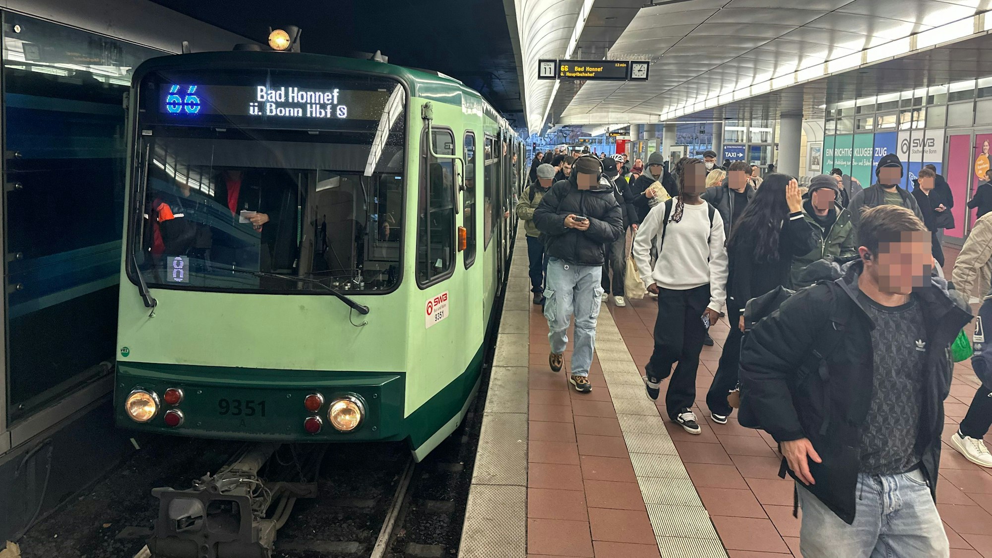 Eine Bahn der Linie 66 steht am Gleis in Siegburg. Menschen steigen aus und ein.
