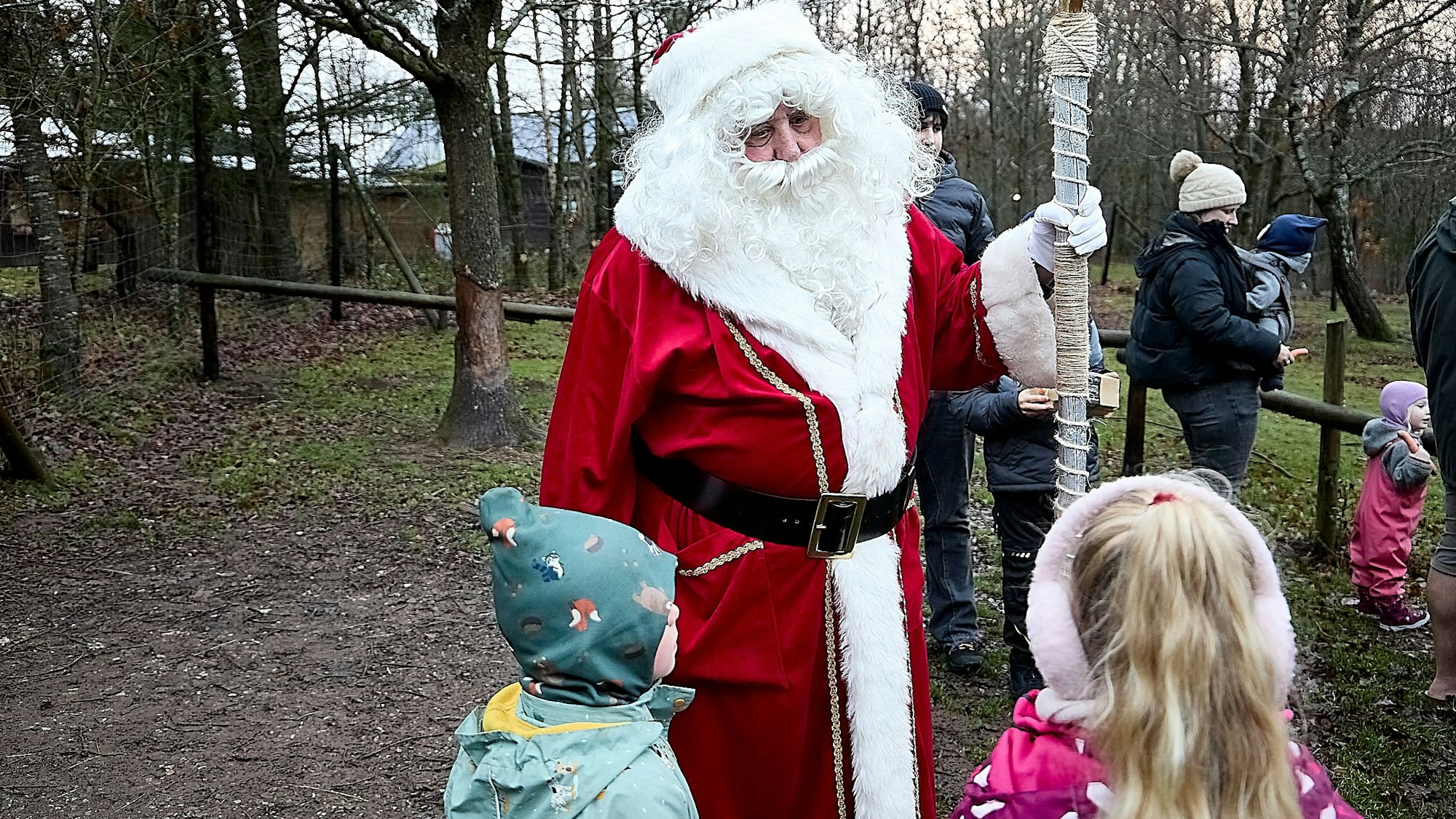 Ein Mann im Nikolauskostüm und weißem Rauschebart redet mit zwei Kindern, die vor ihm stehen.