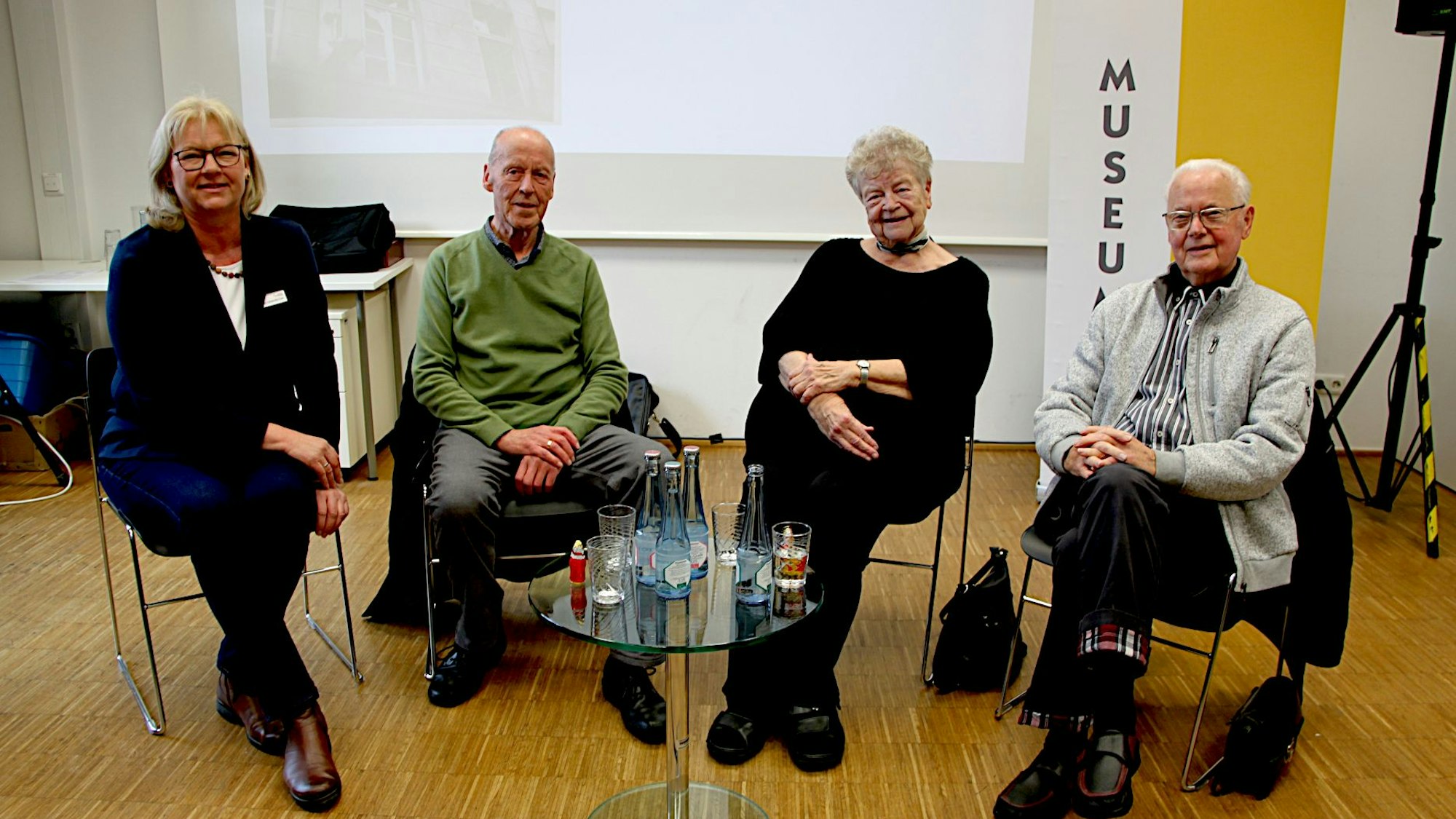 Die Frauen und Männer sitzen an einem Tisch, auf dem Getränke stehen.