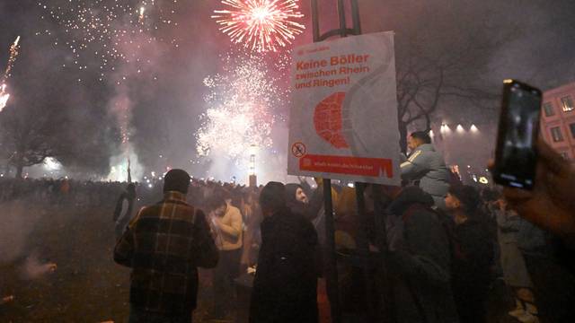Menschen zünden in der Altstadt Feuerwerkskörper vor dem Böllerverbotsplakat um das neue Jahr 2024 willkommen zu heissen.