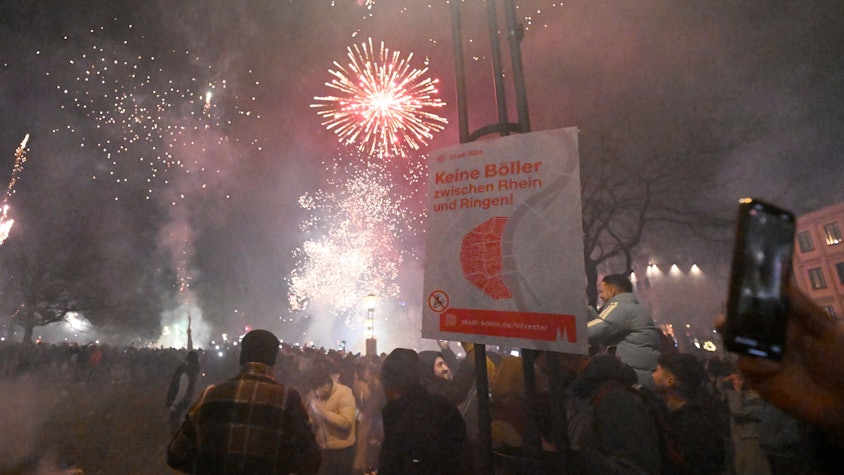 Menschen zünden in der Altstadt Feuerwerkskörper vor dem Böllerverbotsplakat um das neue Jahr 2024 willkommen zu heissen.