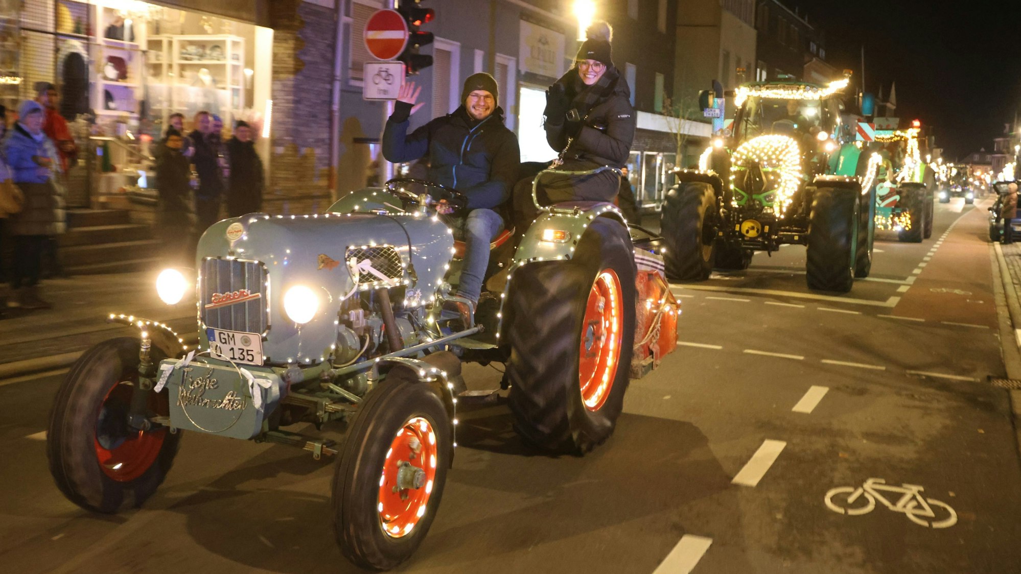Zu sehen ist ein Konvoi weihnachtlich geschmückter Traktoren, die durch die Waldbröler Innenstadt fahren.
