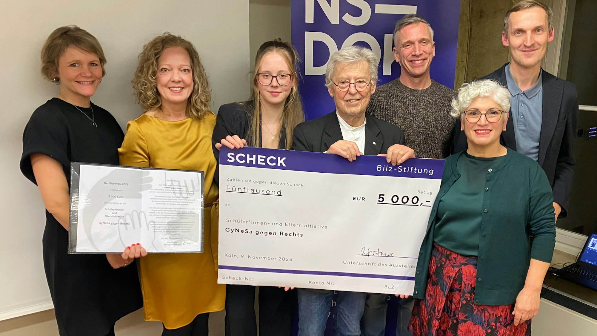 Eine Gruppe von Menschen mit einem symbolischen Scheck.