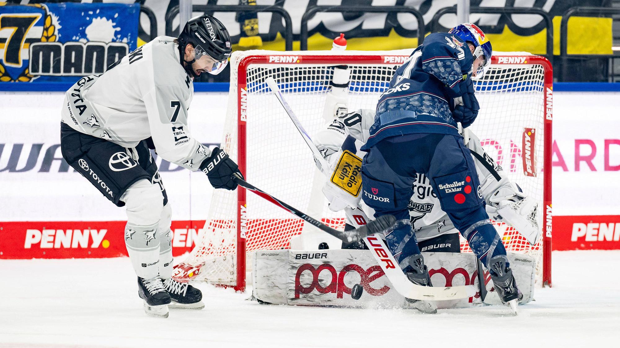 Münchens Adam Brooks beist sich an Oliwer Kaski (l.) und Haie-Goalie Janne Juvonen die Zähne aus.