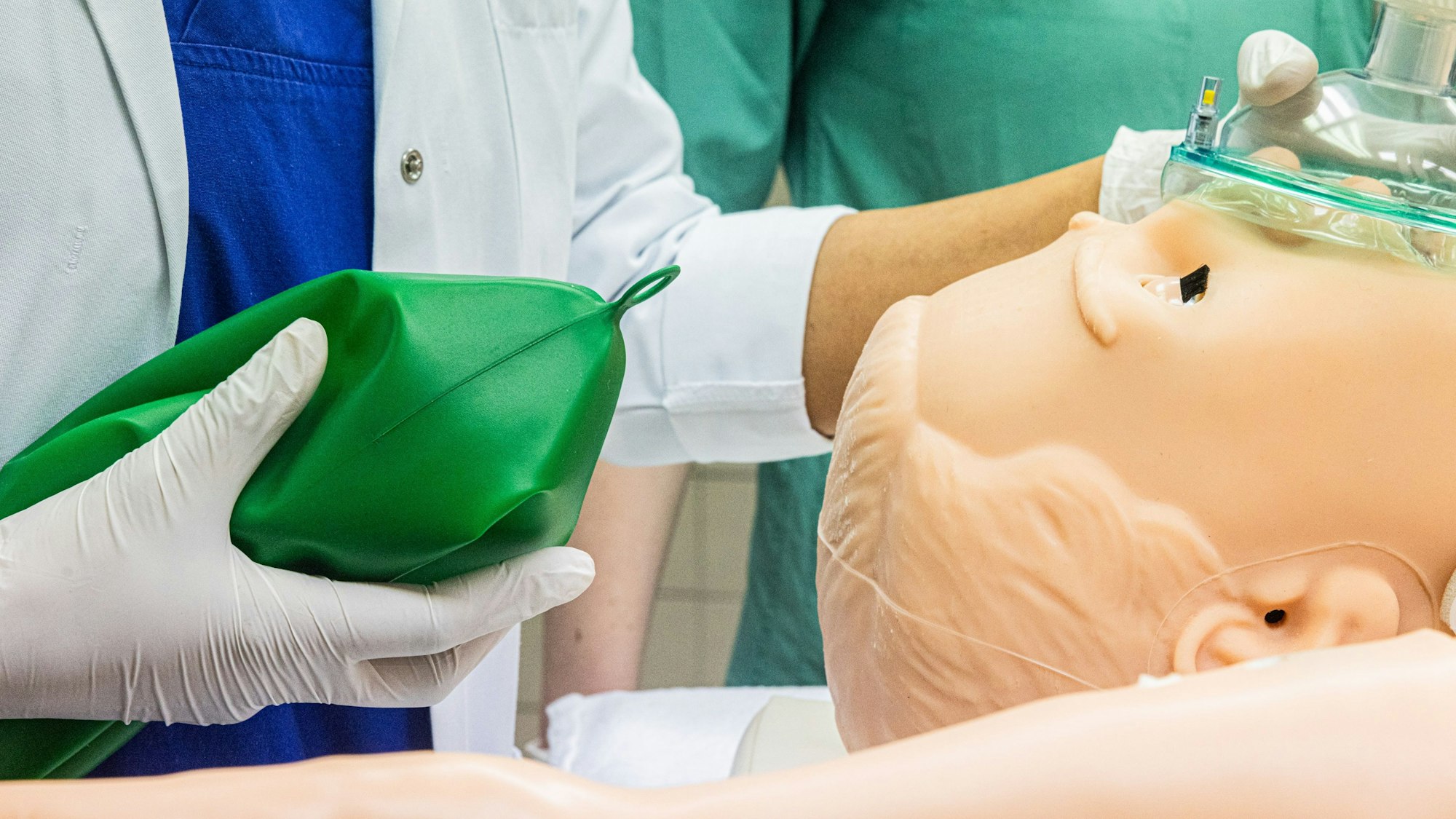 Eine Frau im Kittel beatmet eine Puppe