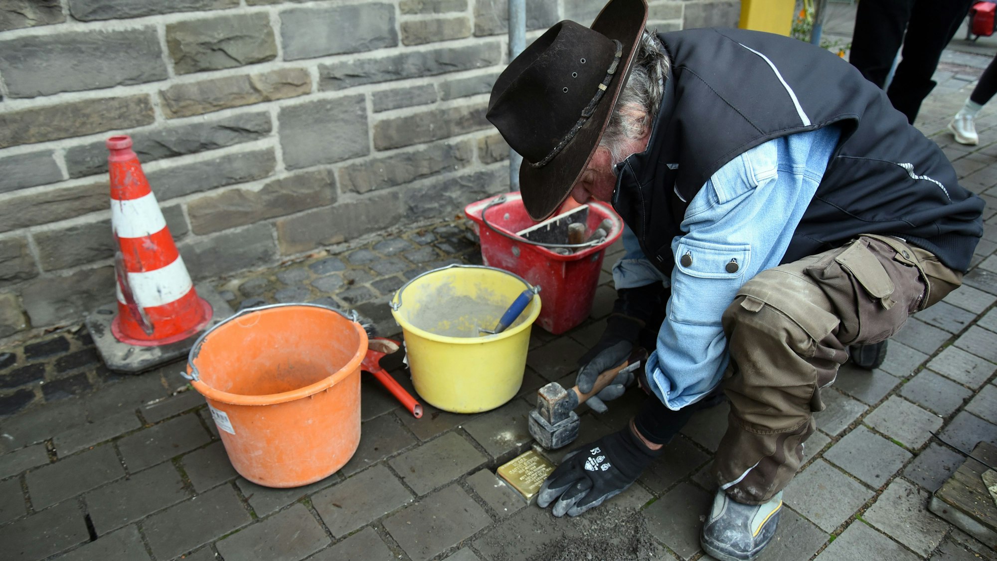 Das Foto zeigt den Künstler Gunter Demnig bei der Verlegung eines Stolpersteins