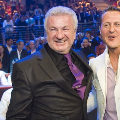 Willi Weber und Michael Schumacher stehen nebeneinander und lachen.