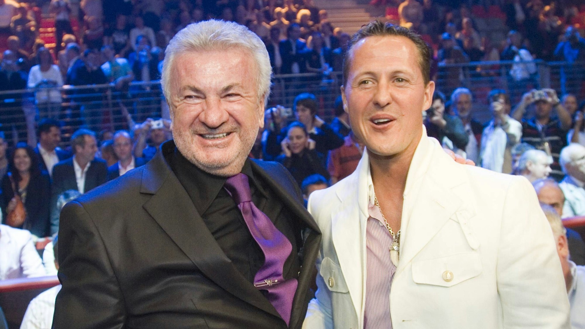 Willi Weber und Michael Schumacher stehen nebeneinander und lachen.