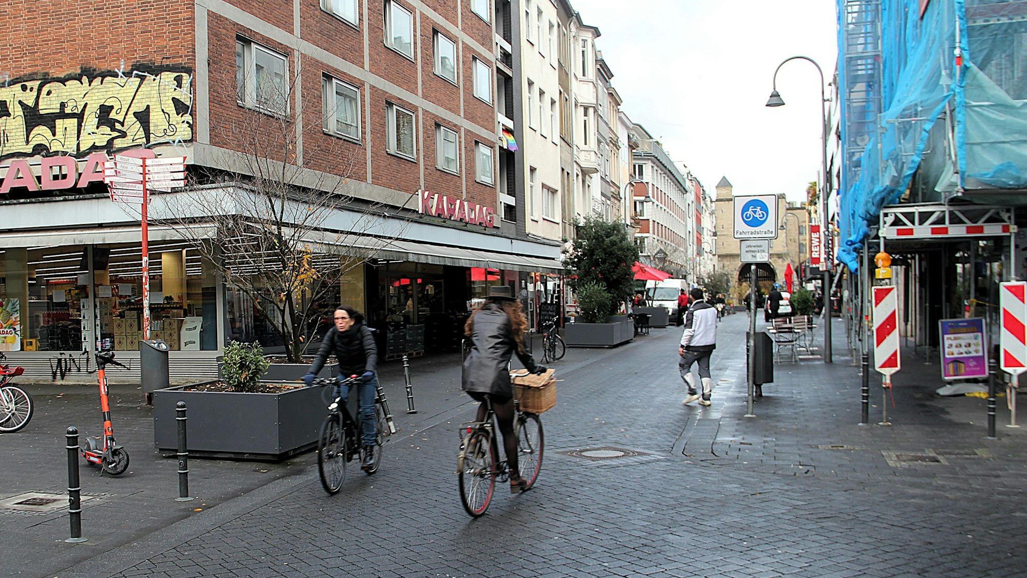 Am Eigelstein sind Radfahrer und Fußgänger unterwegs. Ein Verkehrsschild weist den Straßenabschnitt als Fahrradstraße aus.