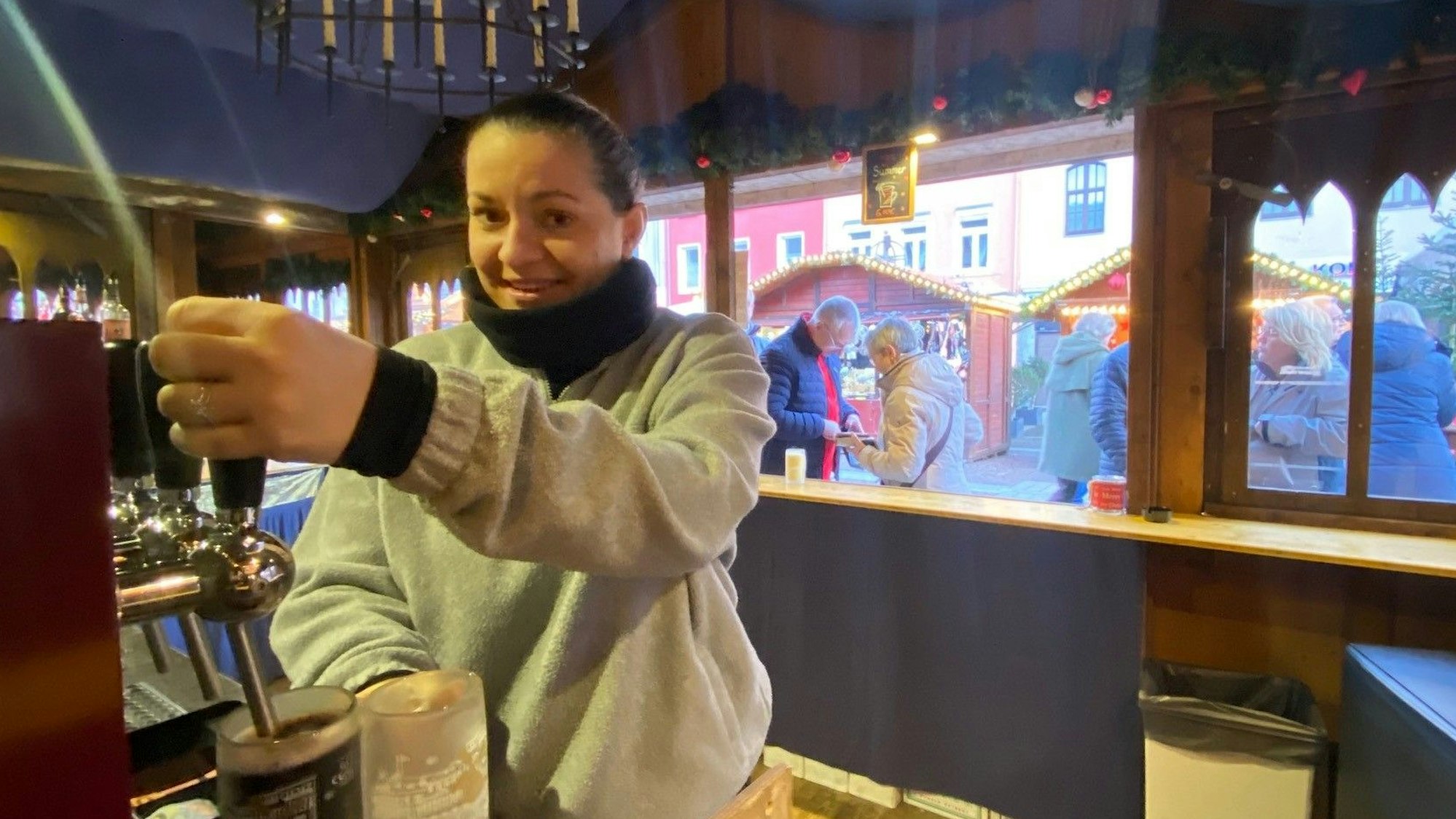 Zu sehen ist eine Frau, die Glühwein zapft.