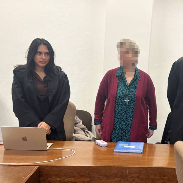 Frau steht vor Gericht, rechts von ihr eine Anwältin, links ein Anwalt.