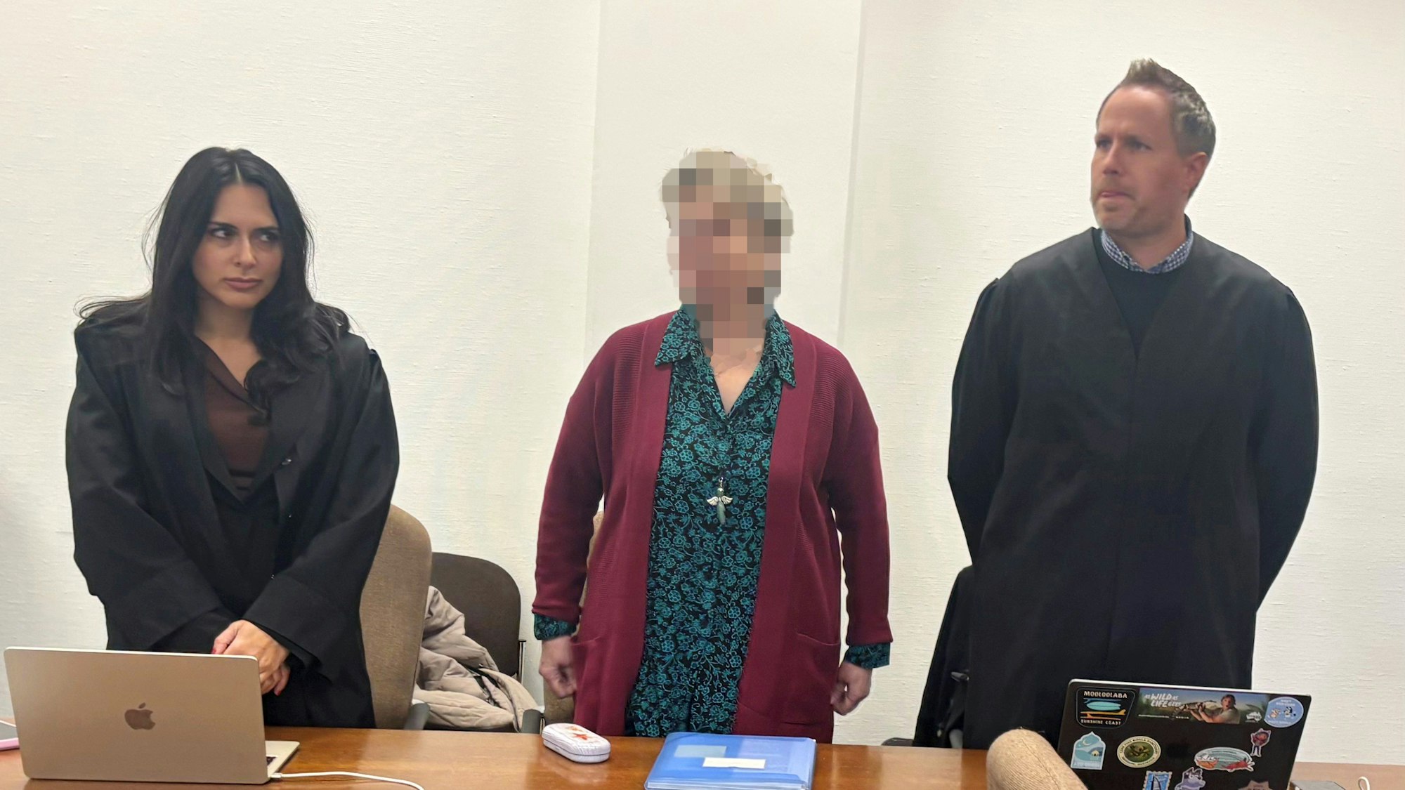 Die Angeklagte steht vor Gericht mit ihren beiden verteidigen.