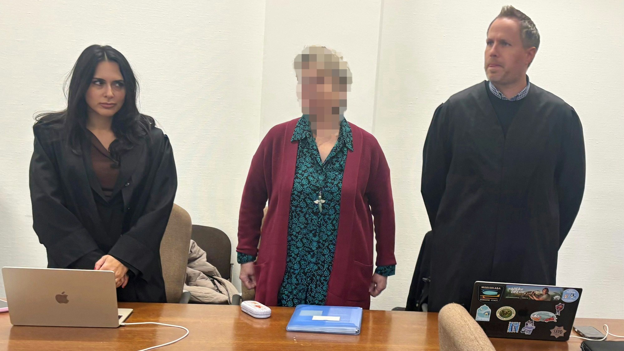 Eine 67-jährige Odenthalerin steht zwischen ihren Verteidigern vor dem Kölner Landgericht.