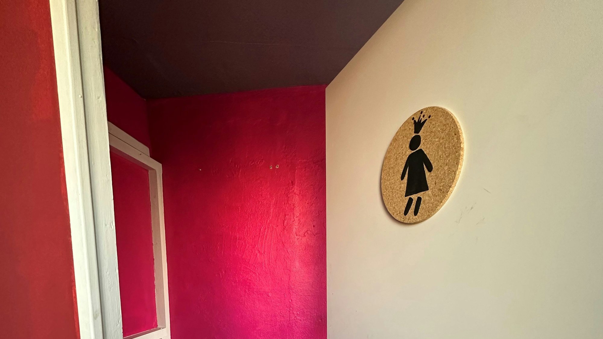 Zu sehen ist die Tür zu einer pink gestrichenen Gästetoilette.