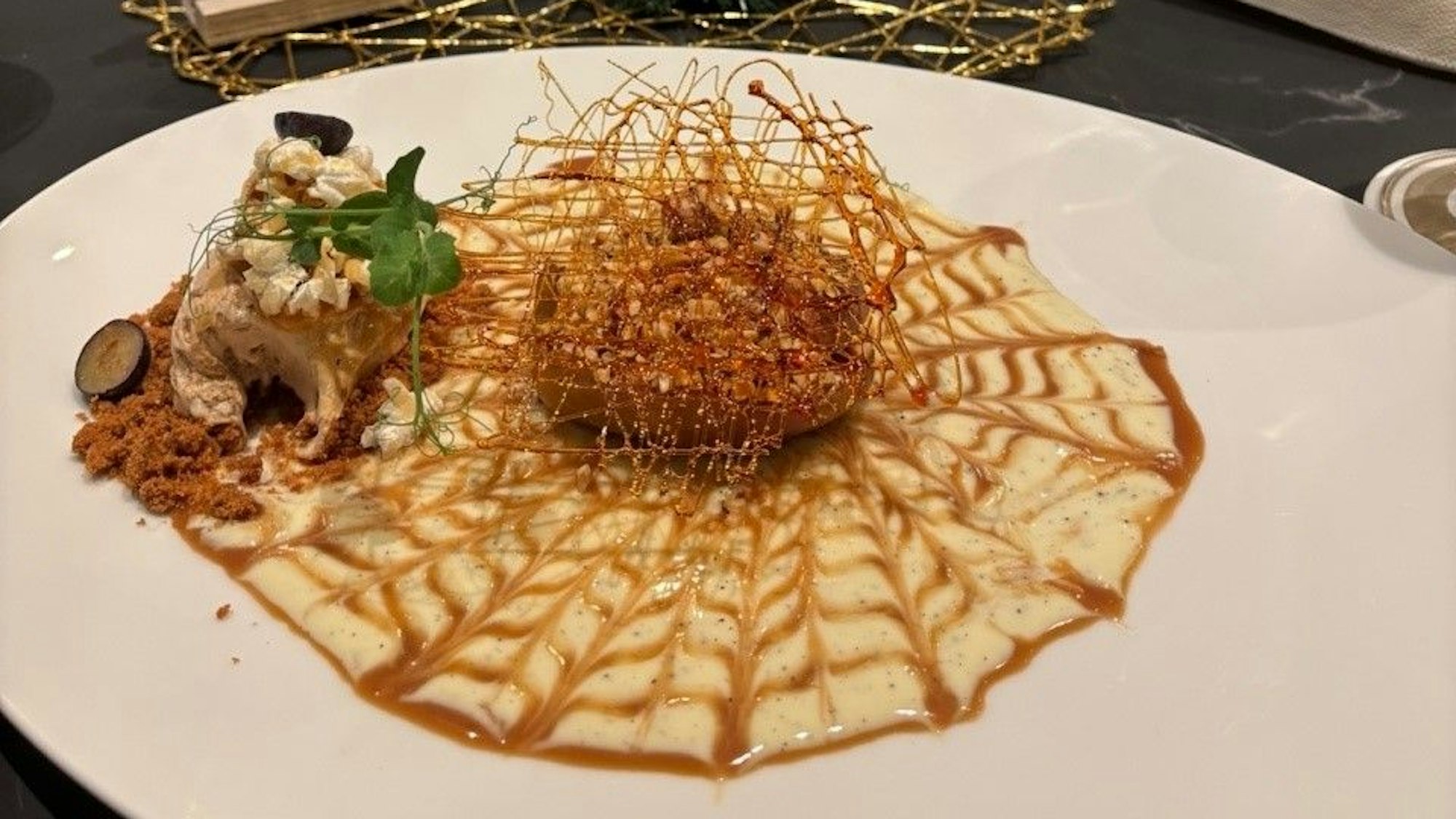 Auf einem Teller ist ein Desert mit Bratapfel, Crème anglaise und Spekulatiuseis zu sehen.