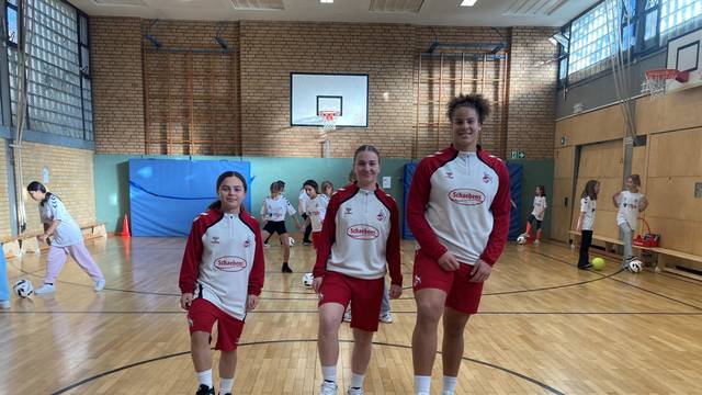 Mädchen spielen in einer Sporthalle Fußball.