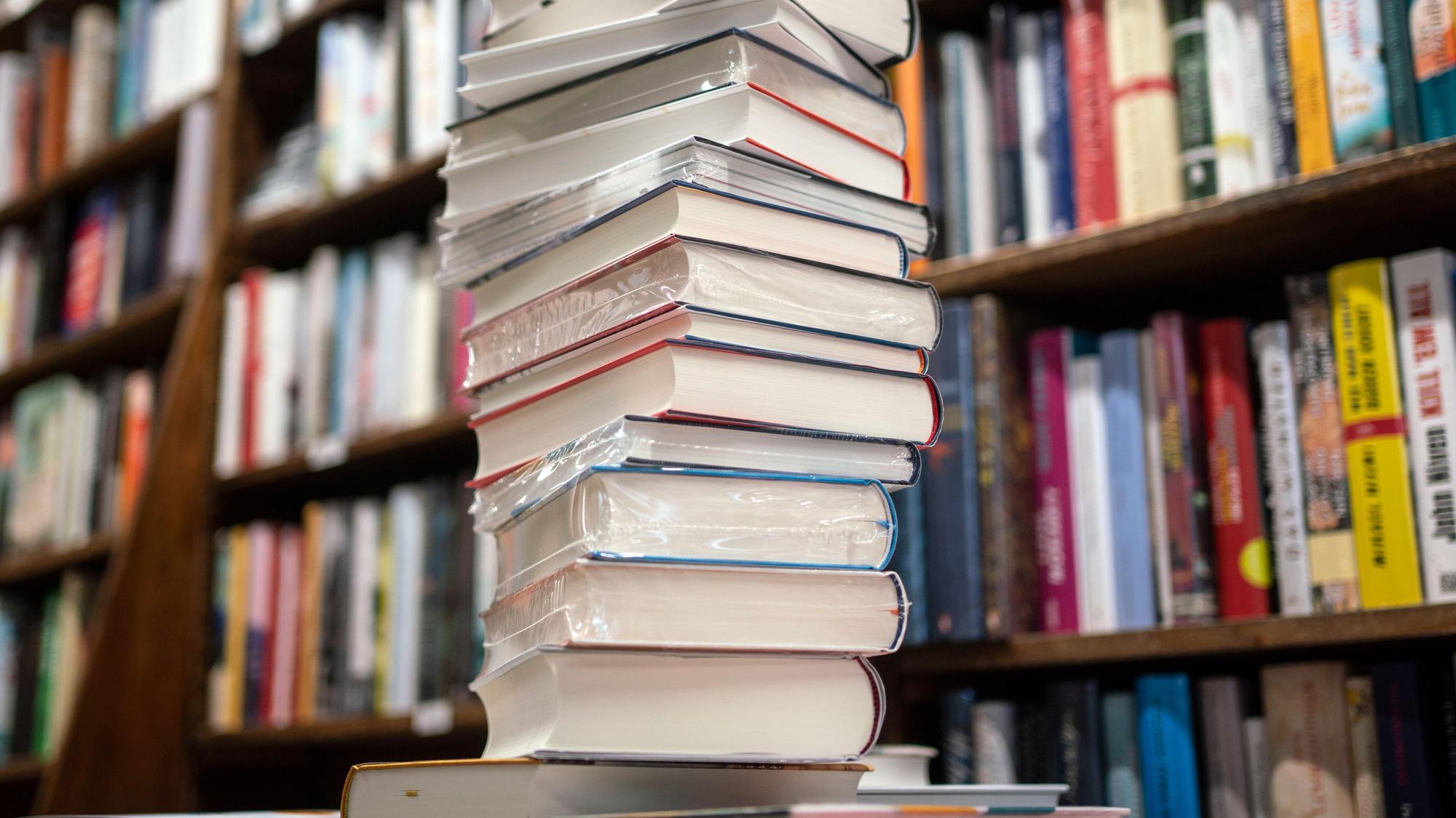 Ein Stapel neuer Bücher liegt auf einem Verkaufstisch in einer Buchhandlung.