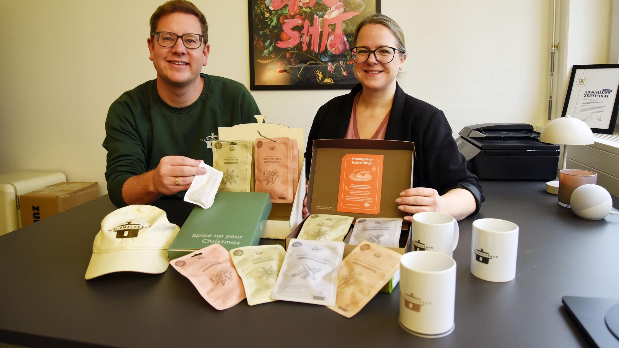 Die zwei Firmengründer sitzen mit Geschmack-Sack-Produkten vor sich an einem Tisch.