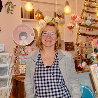 Eine Frau mit blondem Haar steht in einem Laden voller Dekorartikel.