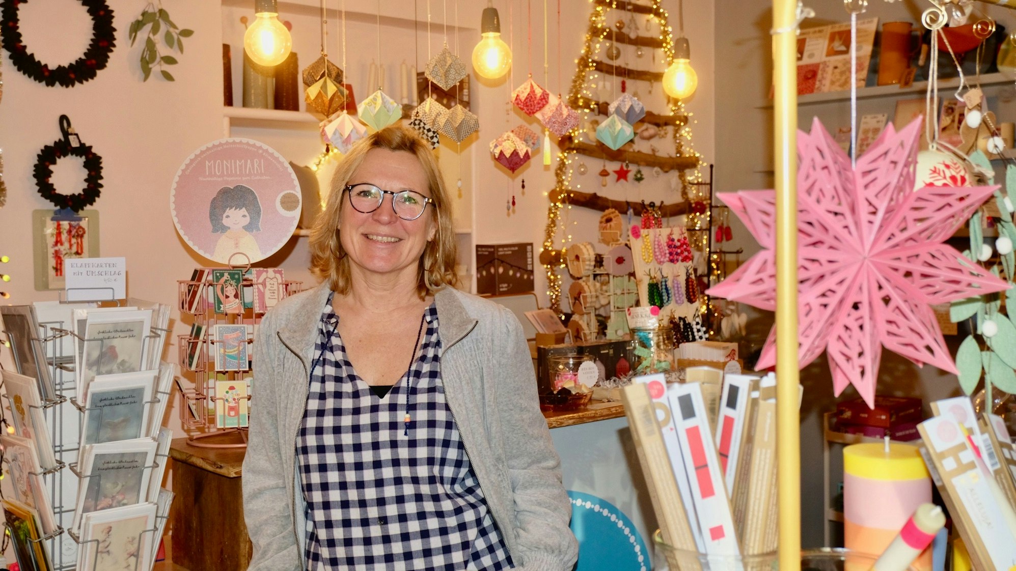 Eine Frau mit blondem Haar steht in einem Laden voller Dekorartikel.