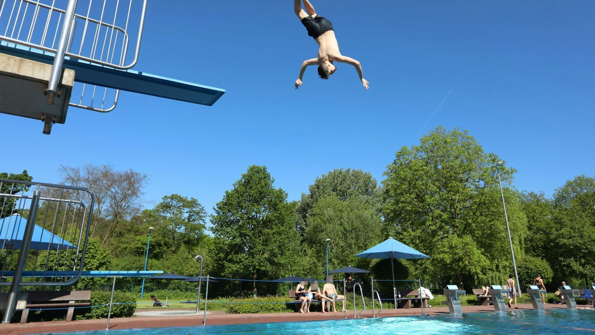 Ein junger Mann springt vom Drei-Meter-Brett kopfüber ins Wasser.