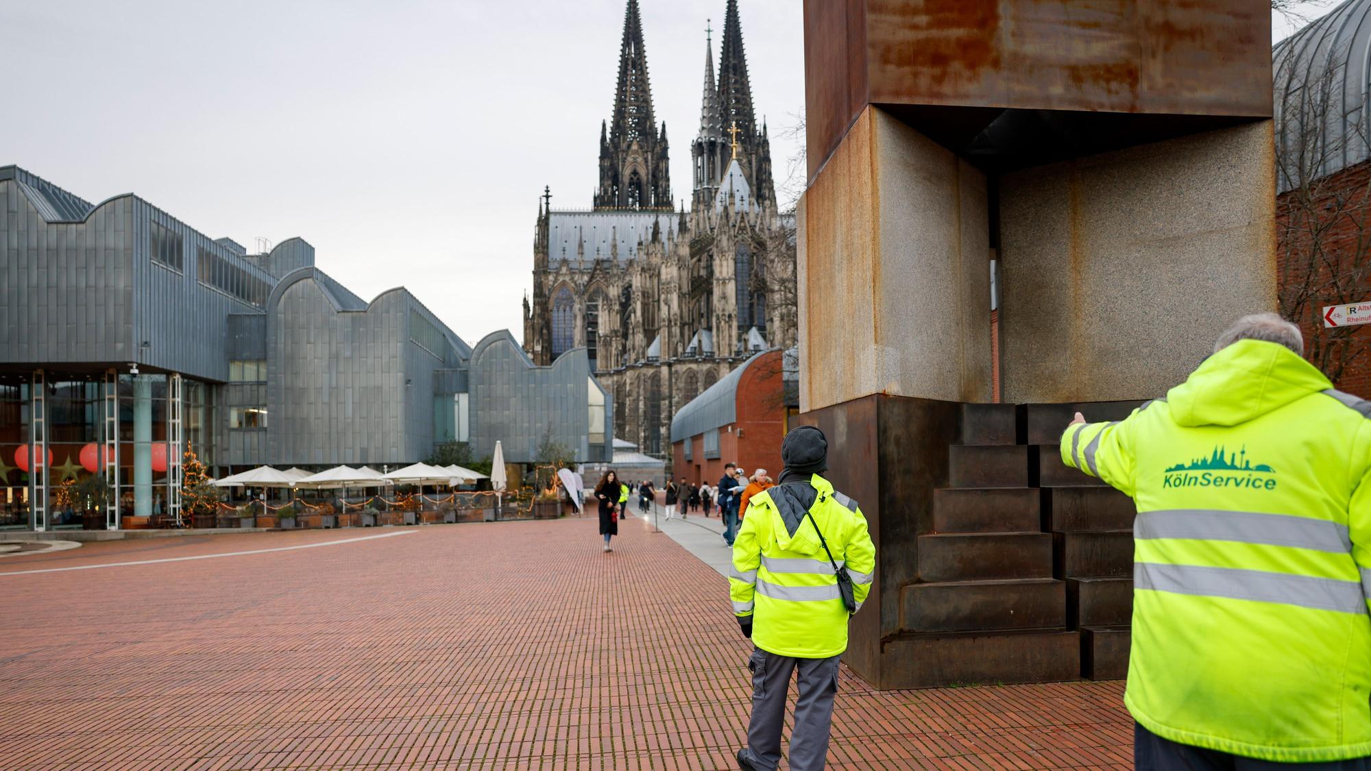 Wachleute der städtischen Firma KGAB bewachen den Heinrich-Böll-Platz.