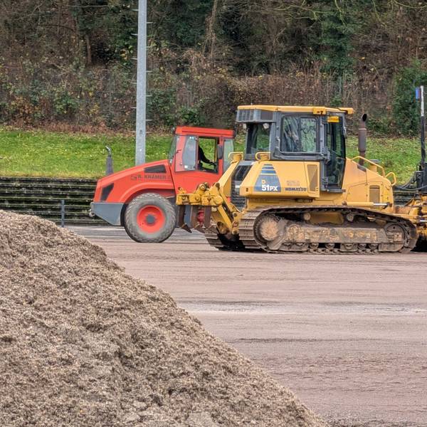 Das Foto zeigt Bagger und einen Sandhaufen auf dem Sportplatz in Berrenrath.