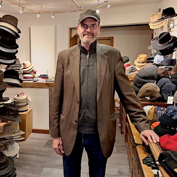 Paul Pauli steht in seinem Geschäft zwischen Regalen voller Hüte und Mützen.