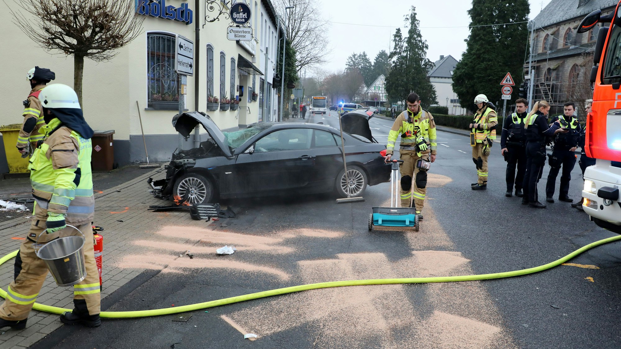 Die Feuerwehr streute ausgelaufene Betriebsstoffe mit Bindemittel ab. Der Unfall ereignete sich unmittelbar neben der Gaststätte in der Ortsmitte von Bergisch Gladbach-Sand