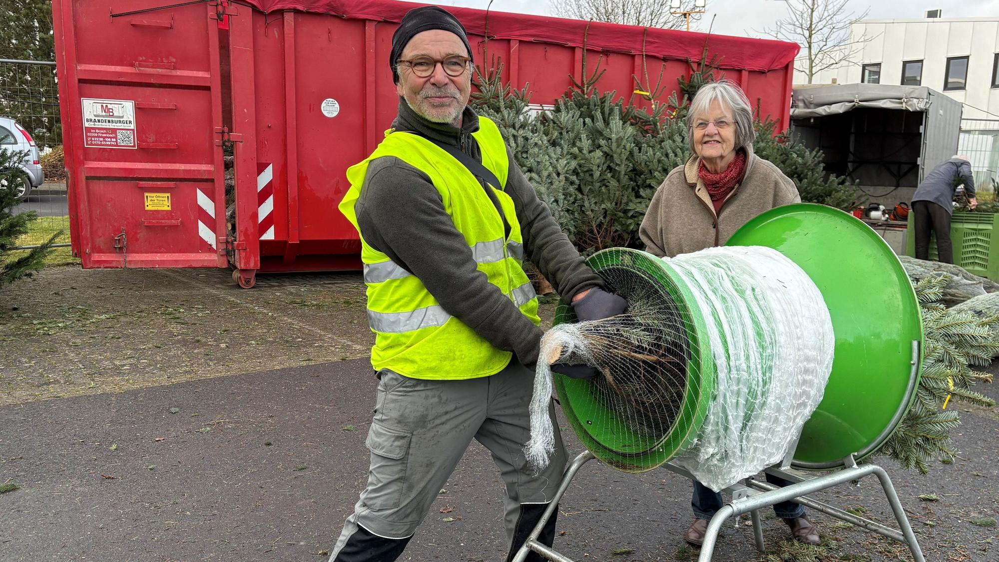 Berta-Marie Hiss ist Stammkundin. Uli Witt verpackt ihren Baum in der Netzmaschine.