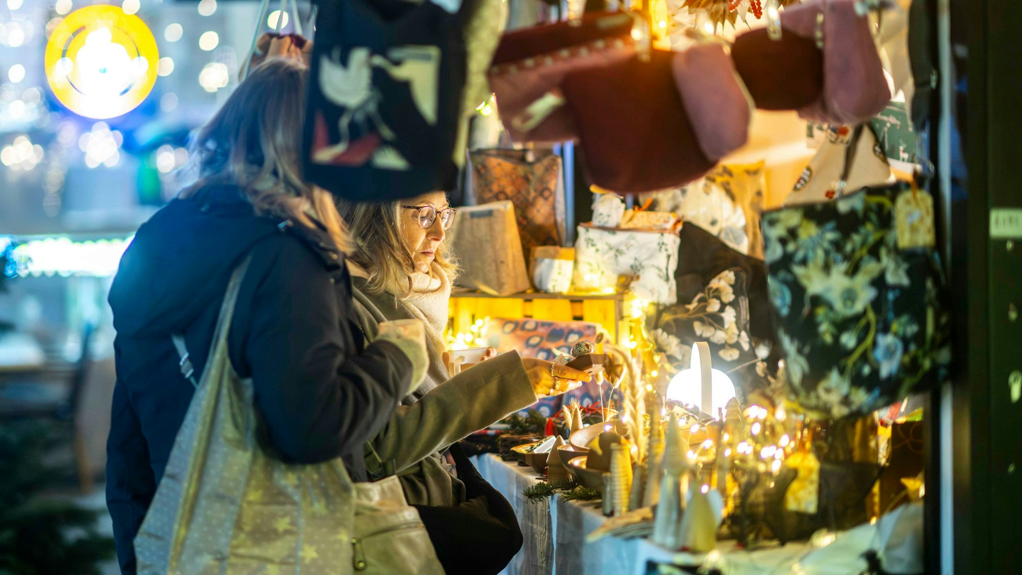 Eine Besucherin schaut prüfend auf die Auslagen in einem Stand.