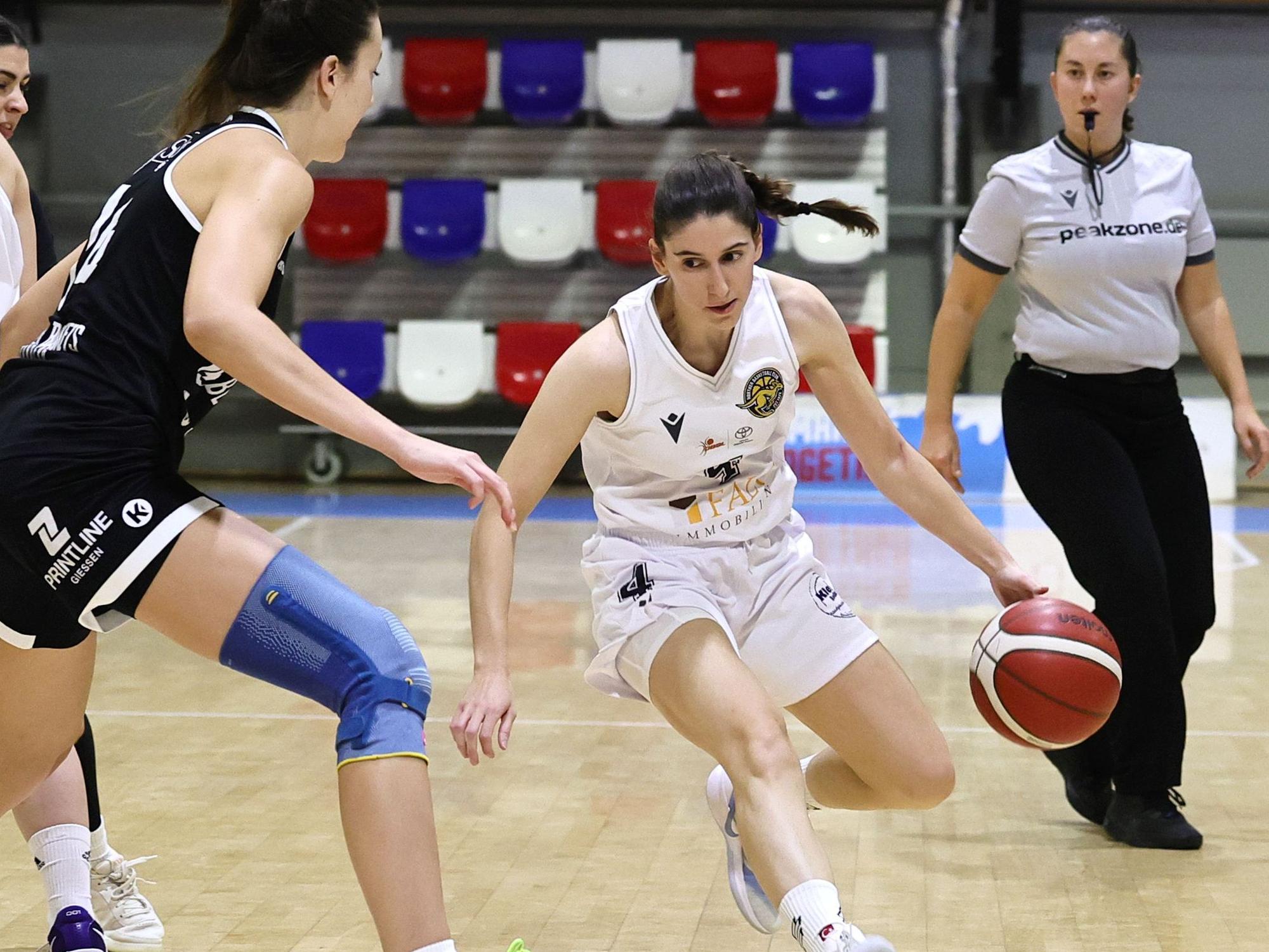 Das Foto zeigt eine Basketballspielerin des Hürther BC mit Ball, die ihre Gegenspielerin um kurven möchte.