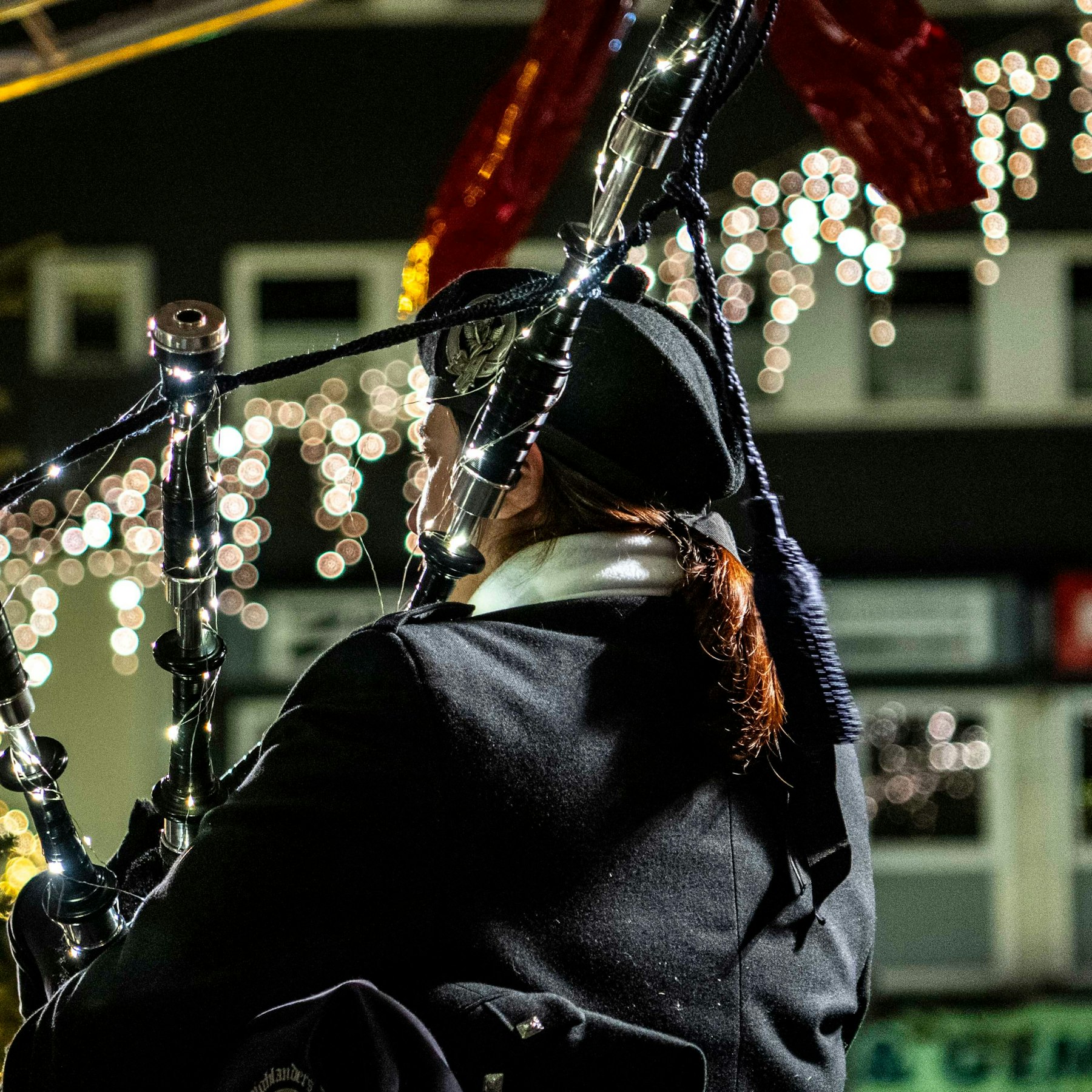 Ein Dudelsackspieler hat sein Instrument mit einer Lichterkette geschmückt.