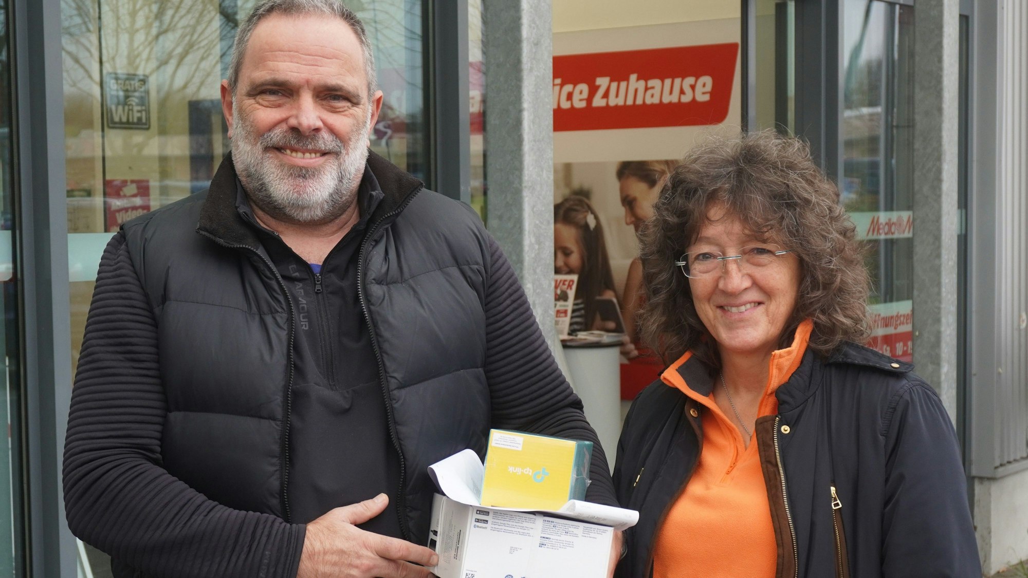 Das Foto zeigt das Paar mit eingekauften Geschenken vor einem Laden.