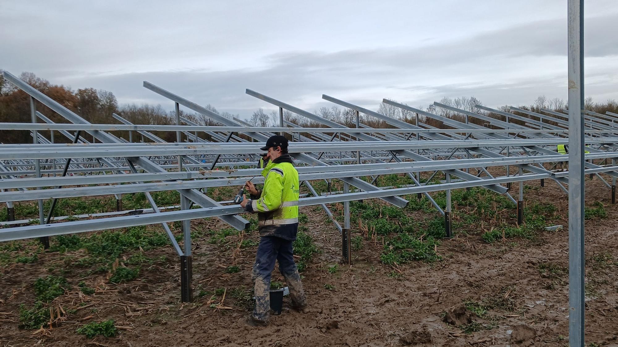 Das Foto zeigt einen Mann, der am Gerüst einer Solaranlage arbeitet.