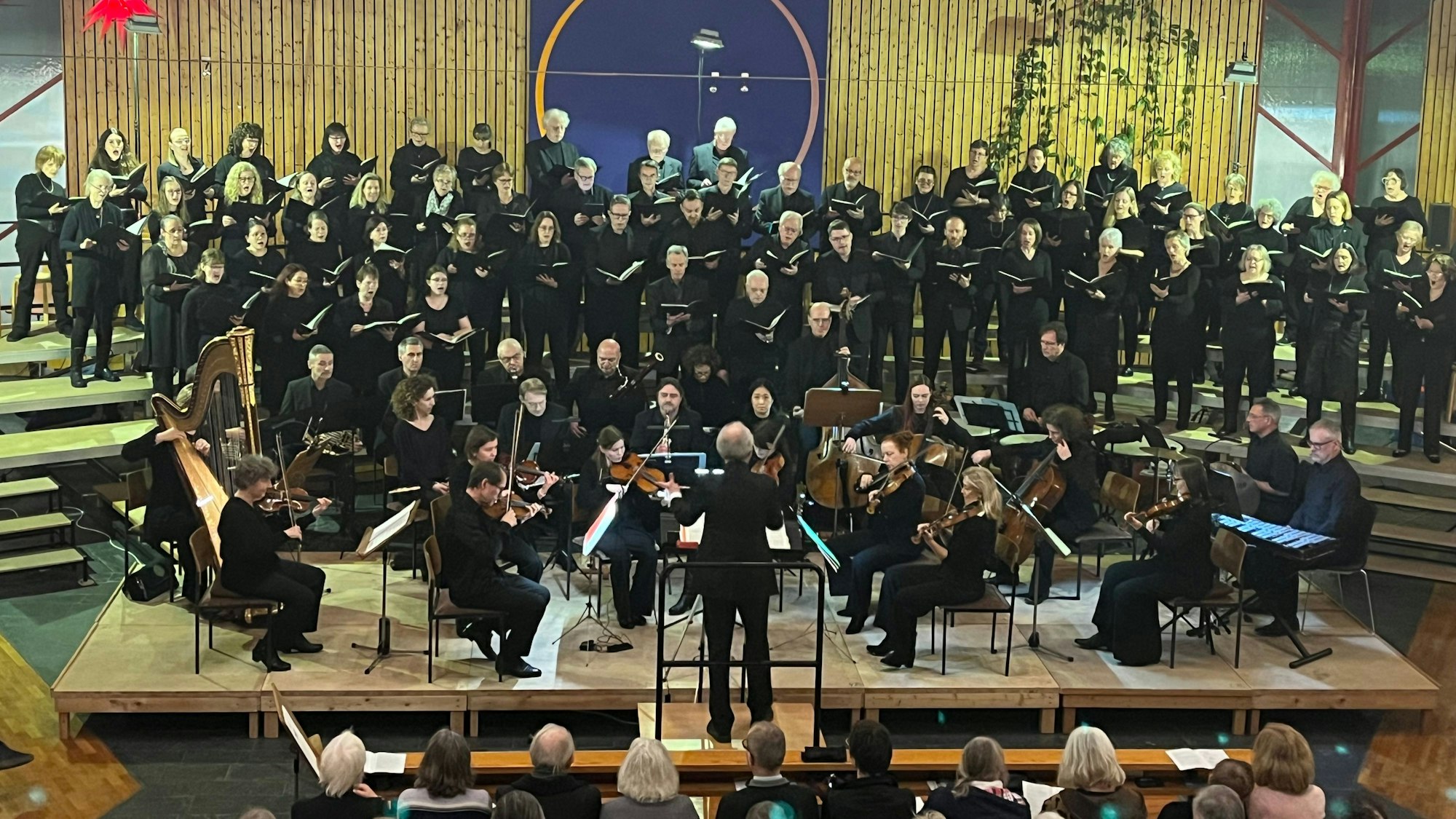 Ein Chor und ein Orchester in Schwarz gekleidet performen gemeinsam in einer Kirche.