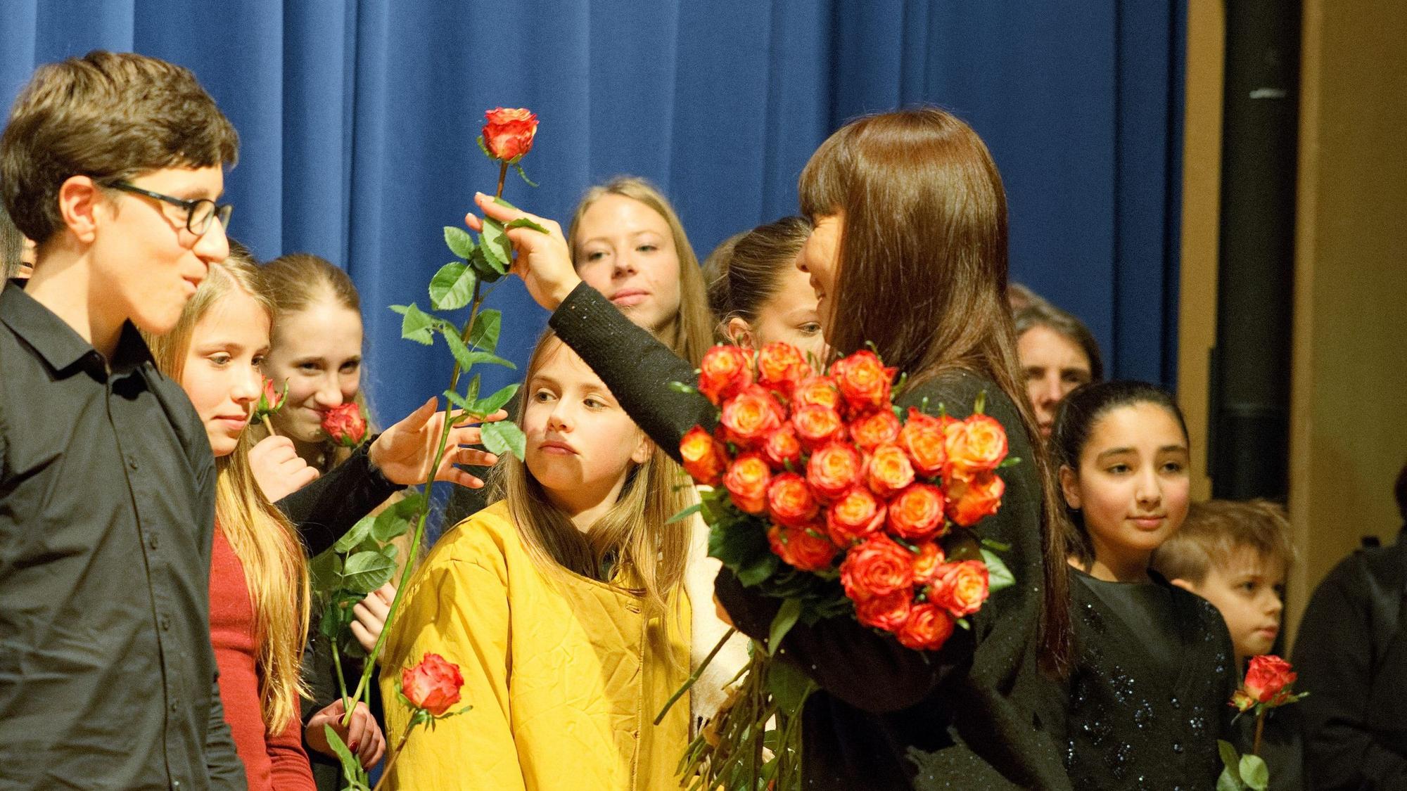Ein Mädchen verteilt rote Rosen.