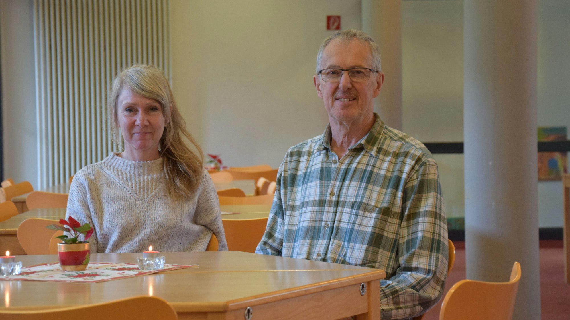 Eine Frau und ein Mann sitzen nebeneinander an einem Holztisch.
