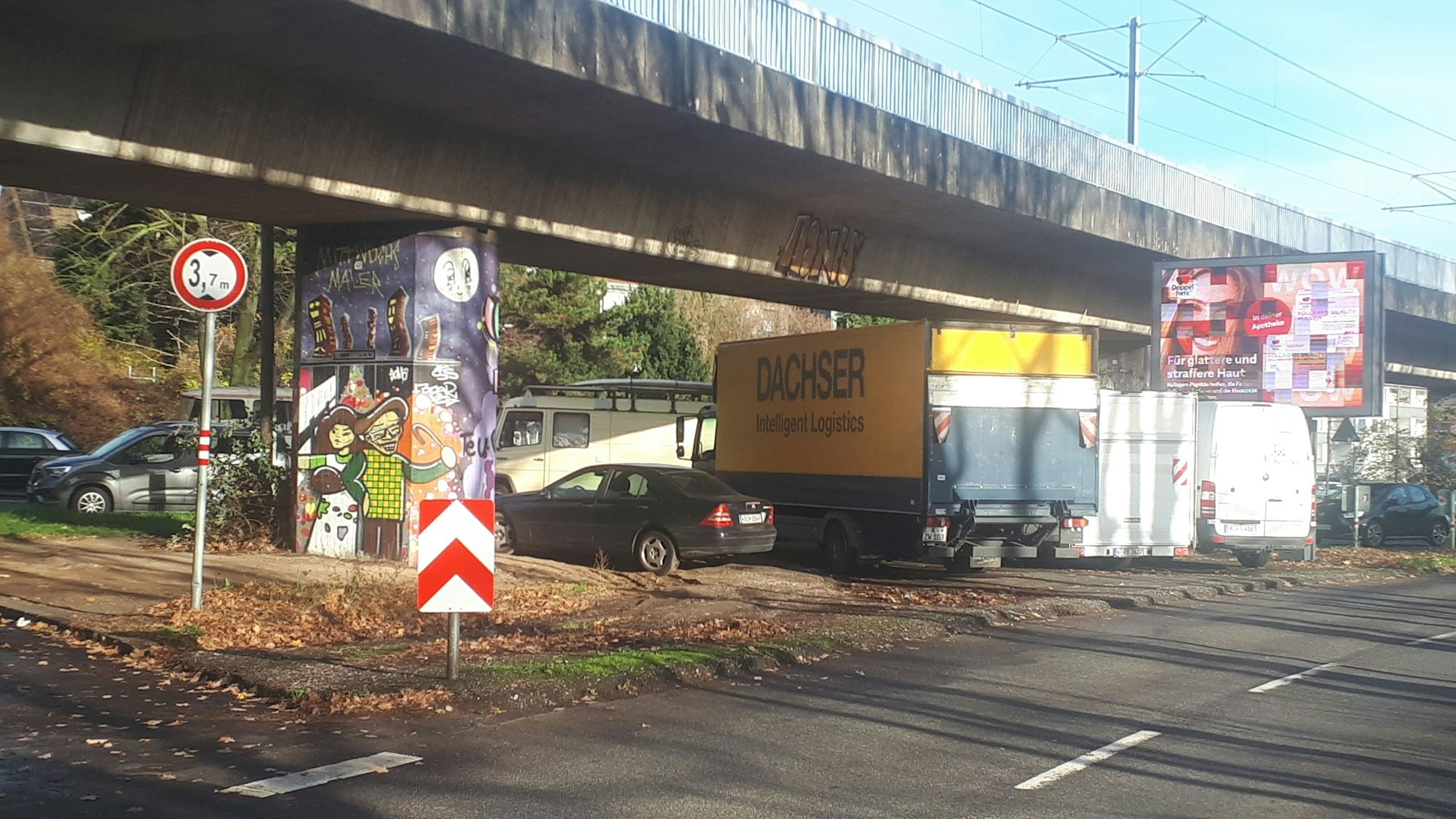 Autos parken zwischen den Pfeilern einer Hochbahntrasse.
