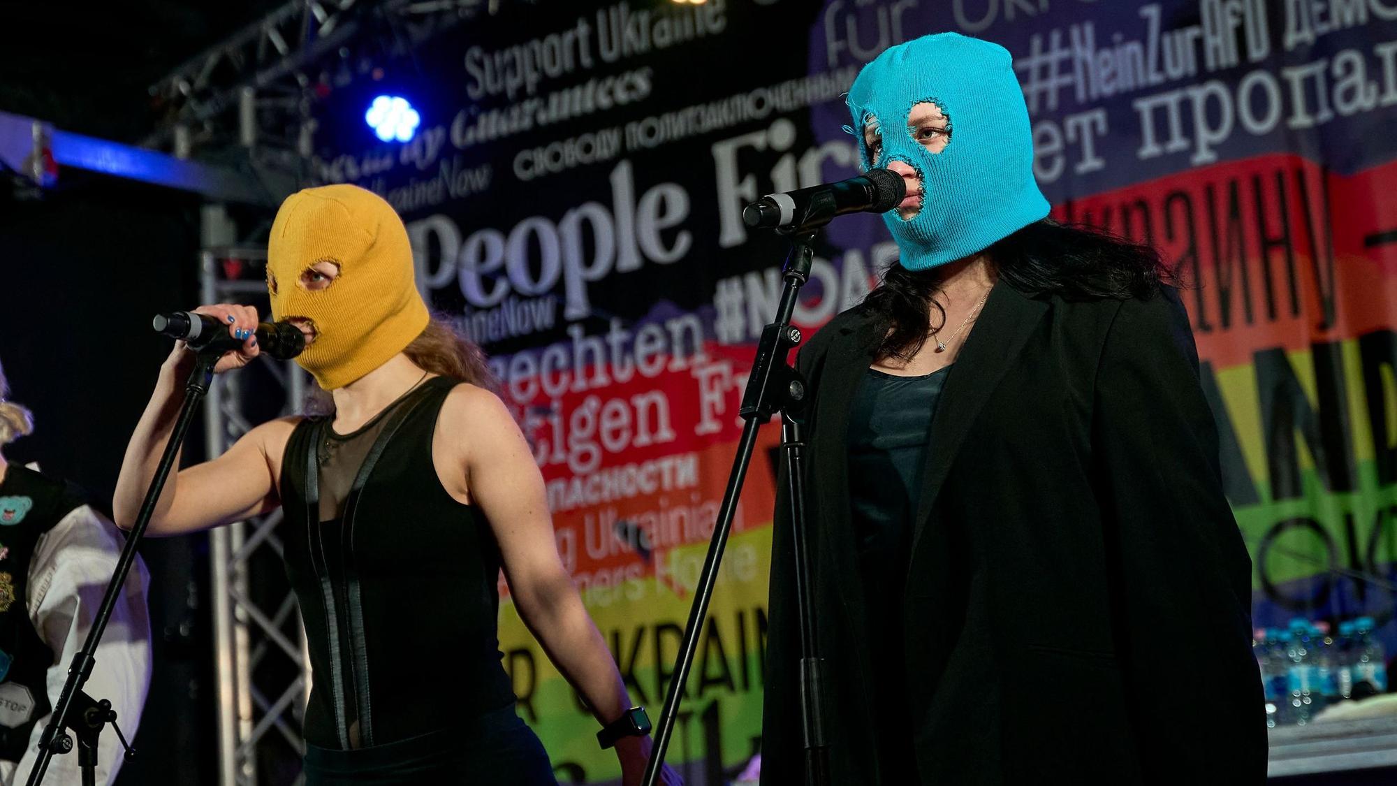 Beim Konzert der Band Pussy Riot gegen den Krieg in der Ukraine am Brandenburger Tor in Berlin stehen Bandmitglieder mit Stoffmasken auf der Bühne.