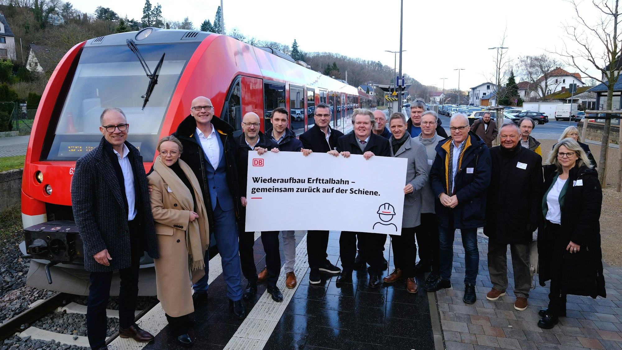 Das Foto zeigt eine Gruppe von rund 20 Personen, die mit einem Plakat vor einem Nahverkehrszug am Bahnsteig in Bad Münstereifel stehen.