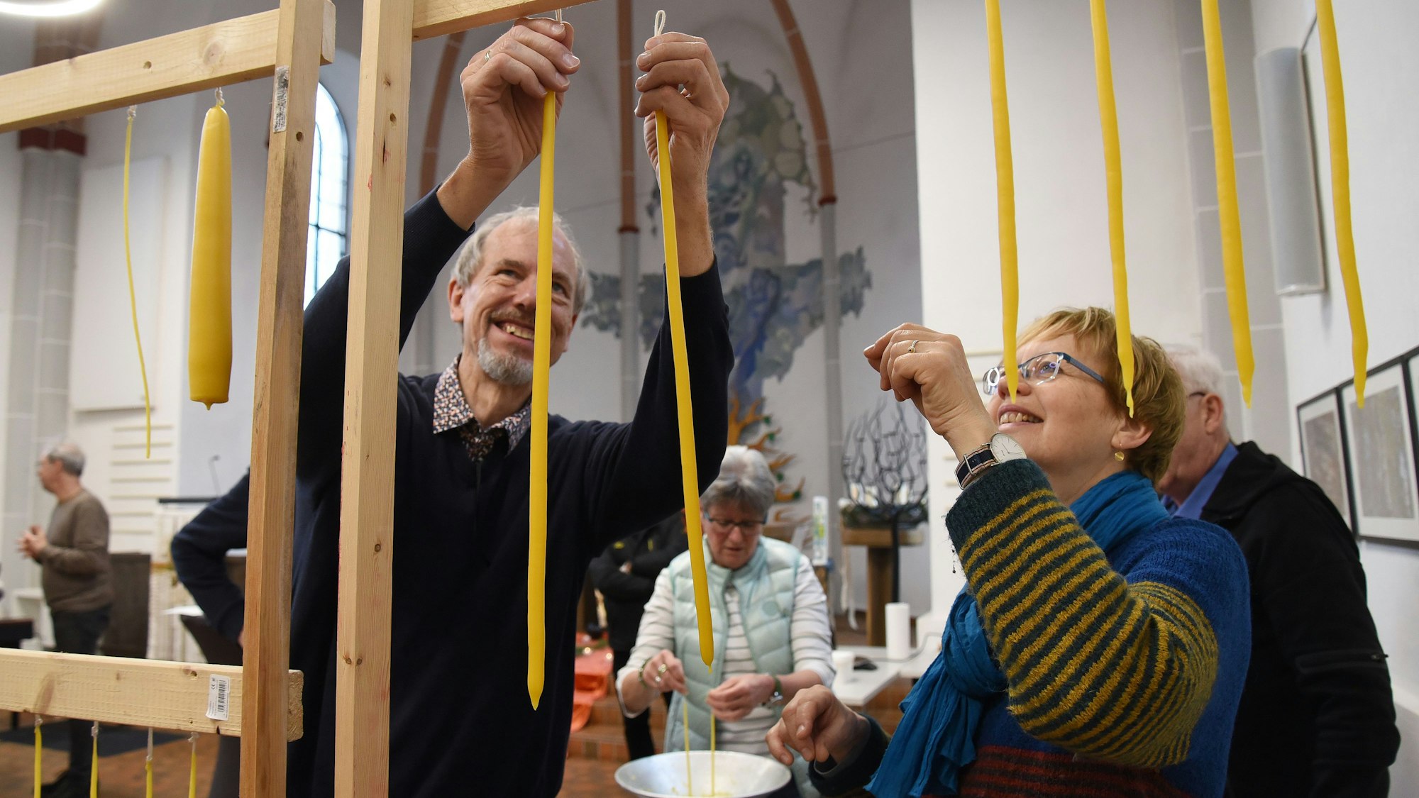 Mehrere Menschen hängen selbst gezogene Kerzen auf.