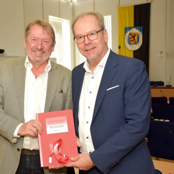Das Foto zeigt zwei Männer bei einer Übergabe einer Petition.