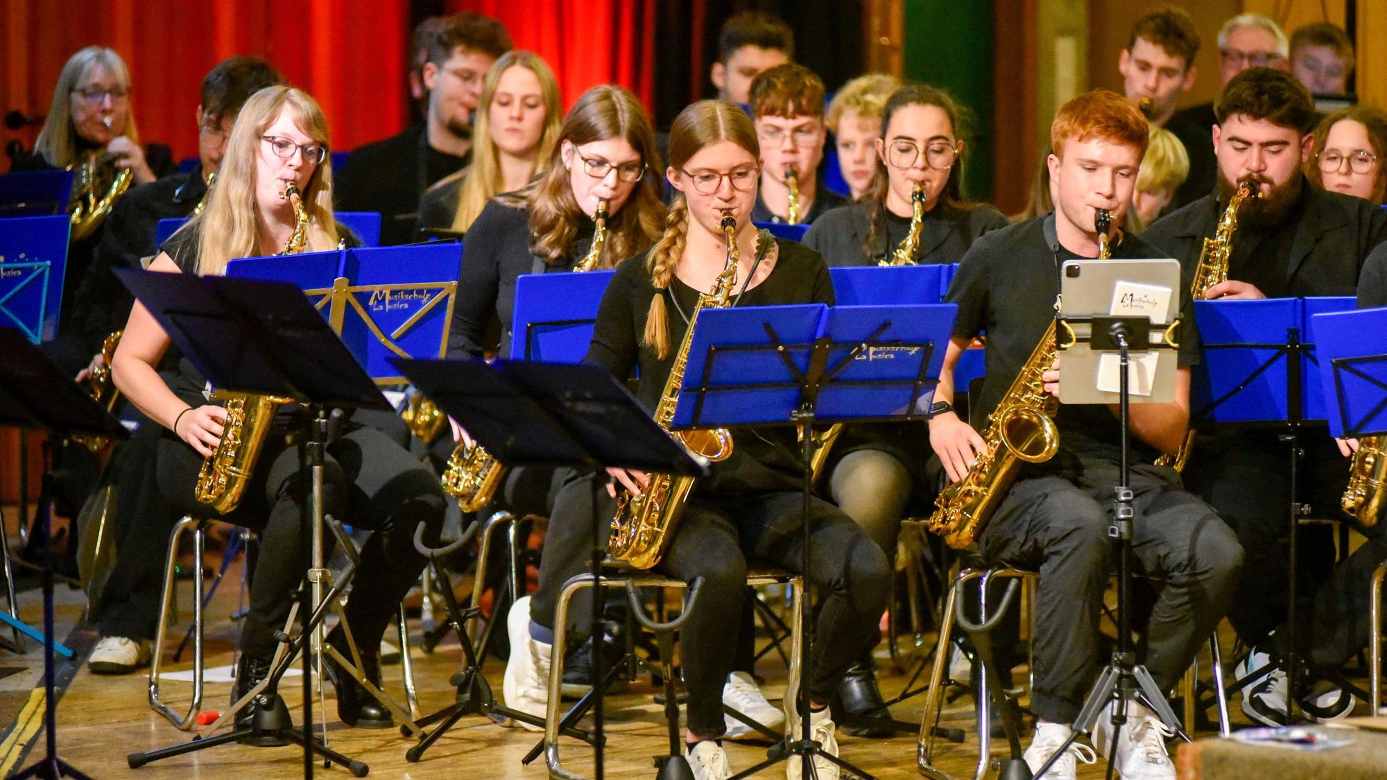 Das Bild zeigt junge Musikschüler mit Blasinstrumenten, vor ihnen stehen Notenständer.